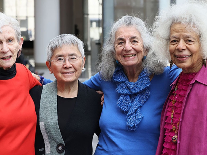 Four older women pose and smile